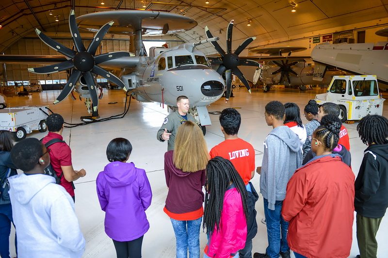 Volunteer AWF1 Ryan Pendexter, a part of the aircrew for the E-2D at VX-20, introduces students from Charles County public middle schools to the E-2D Hawkeye aircraft and its importance to the mission of sea going fleets by keeping an eye on nearby airspace.
