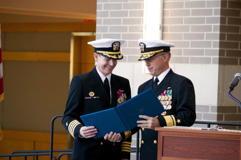 Rear Adm. Brian Corey (right), who oversees the Program Executive Office for Unmanned Aviation and Strike Weapons (PEO (U&W)) congratulates Capt. Jeff Dodge, who will retire from the Navy after 27 years of service, during the Multi-Mission Tactical Unmanned Aerial Systems program office (PMA-266) change of command ceremony Oct. 18 in Patuxent River, Md. (U.S. Navy photo)