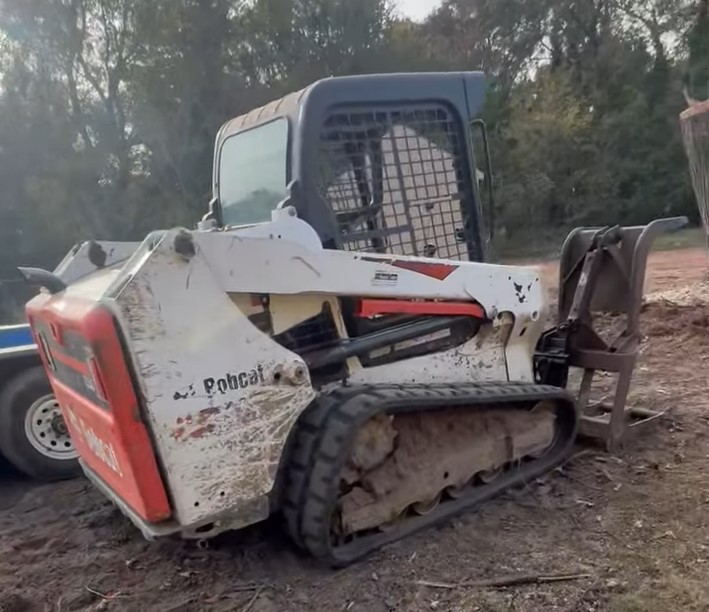 Publicly shared image shows a Bobcat T550 tracked loader moving large cut tree trunks on a worksite. The machine matches the equipment listed in court filings as stolen and later returned.